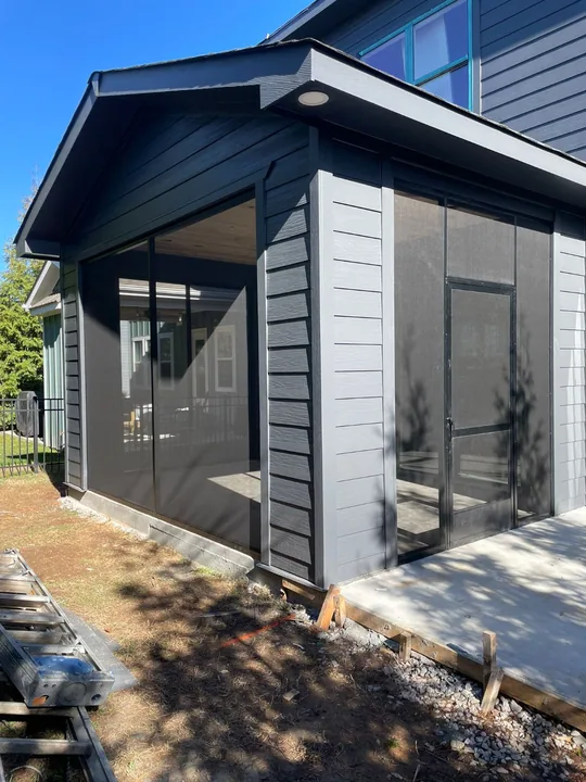 Screen porch entrance with a black screen door and wood ceiling