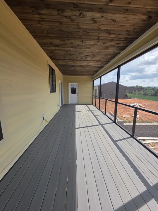 Inside a screened porch with a wood ceiling and gray flooring