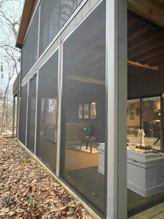 Screen porch enclosure beside a wooded yard