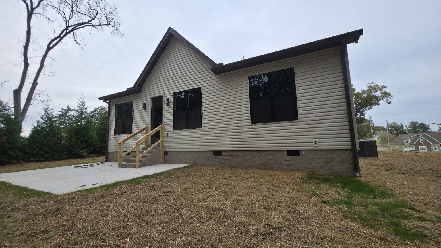 Wide rear view of light-colored vinyl siding with dark windows and roof trim.